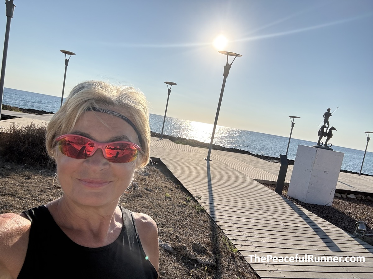 Jackie running in Protaras on boardwalk Jackie on the coastal boardwalk at sunrise beside a bronze statue of a figure riding a seahorse