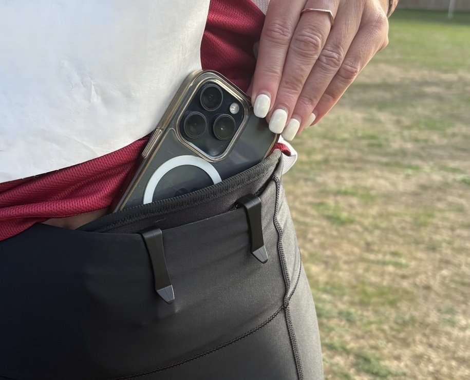 A phone being slipped into a #PRPocket clipped inside the waistband of running leggings